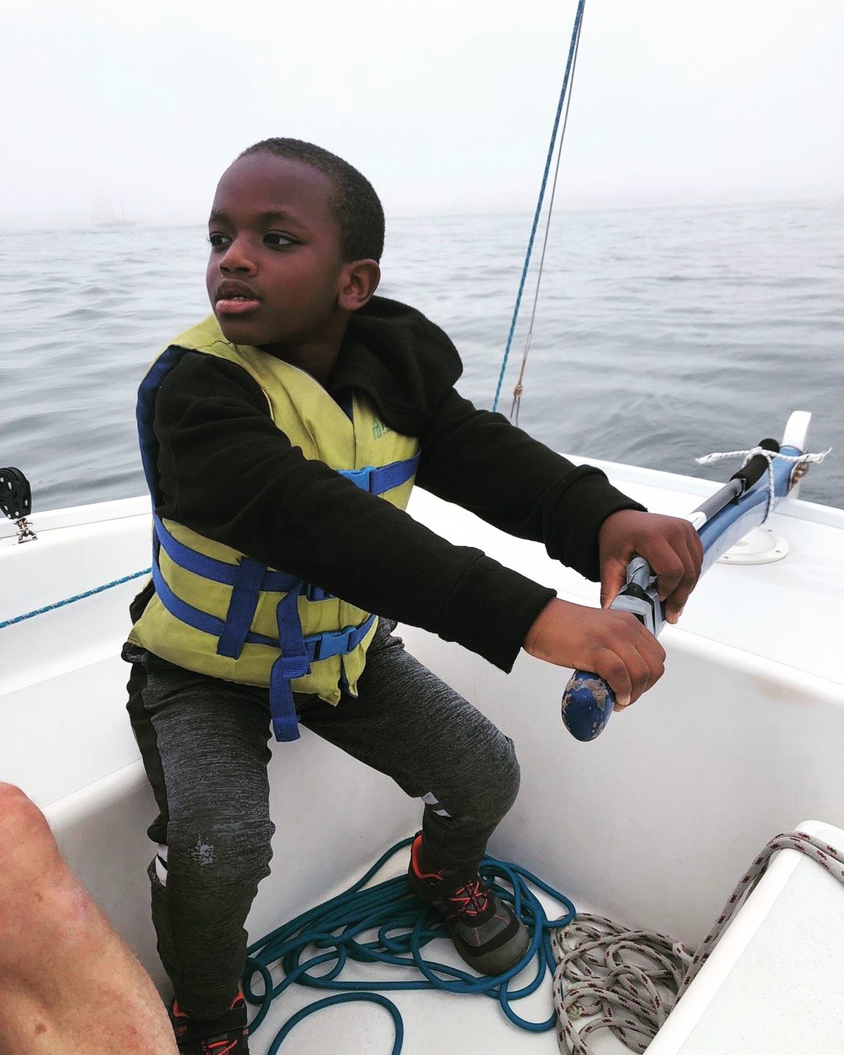 a boy steers a sailboat